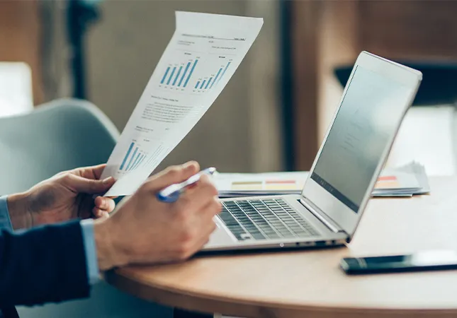 A person at their desk holding a document.
