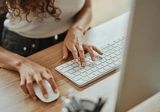 A person using a mouse and typing on a computer keyboard.