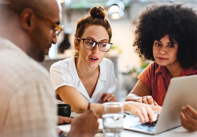 Three people looking at a laptop.