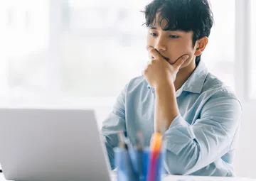 A man looking at a laptop screen and thinking.