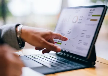 A person pointing at a graph on a tablet computer.