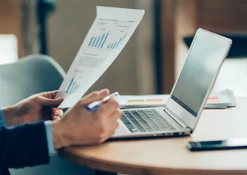 A person at their desk holding a document.