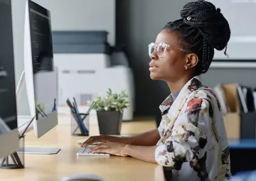 A woman using a mouse and looking at a computer screen.
