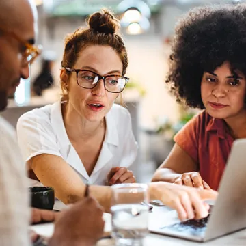 Three people looking at a laptop.